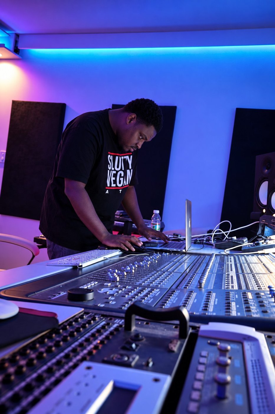 ELUS at work on a large mixing console in a Bronx studio, lit in blue and purple